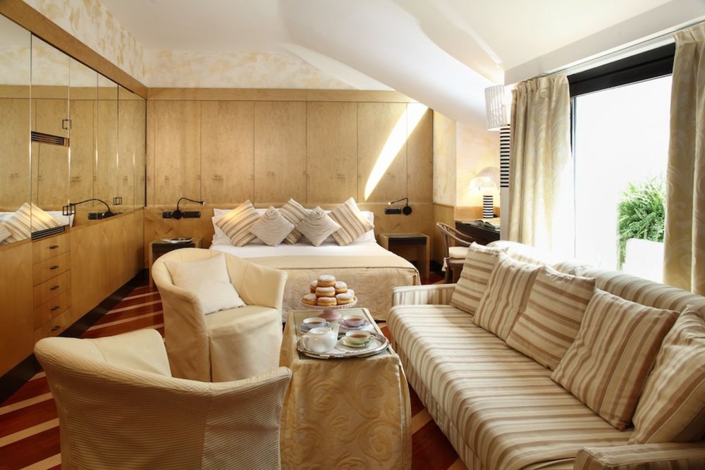 Stylish bedroom with sofa seating at Hotel Sanpi Milano