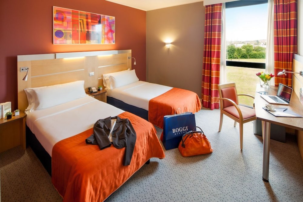 Twin bedroom with orange accents at Idea Hotel Milano San Siro Milan