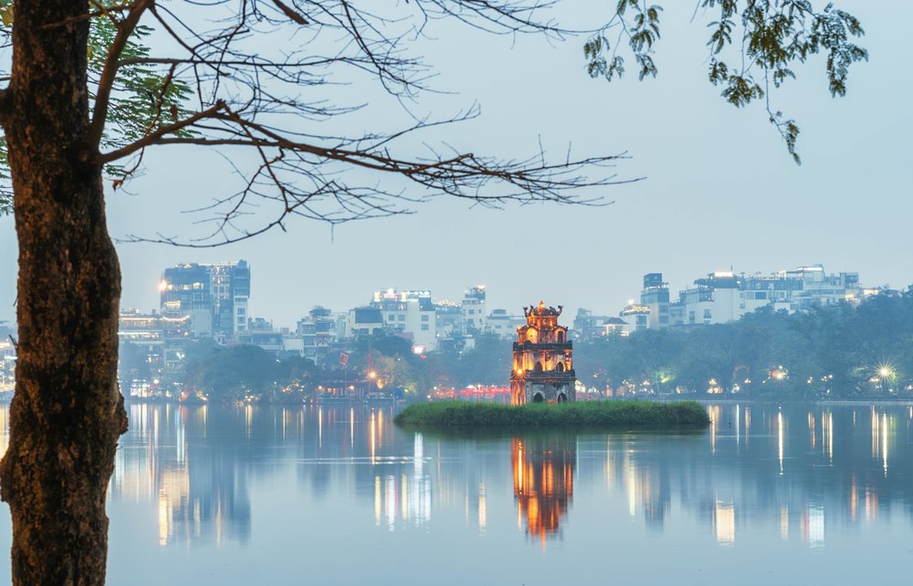 Hoan Kiem Lake and Turtle Tower reflected in calm water at sunset in Hanoi