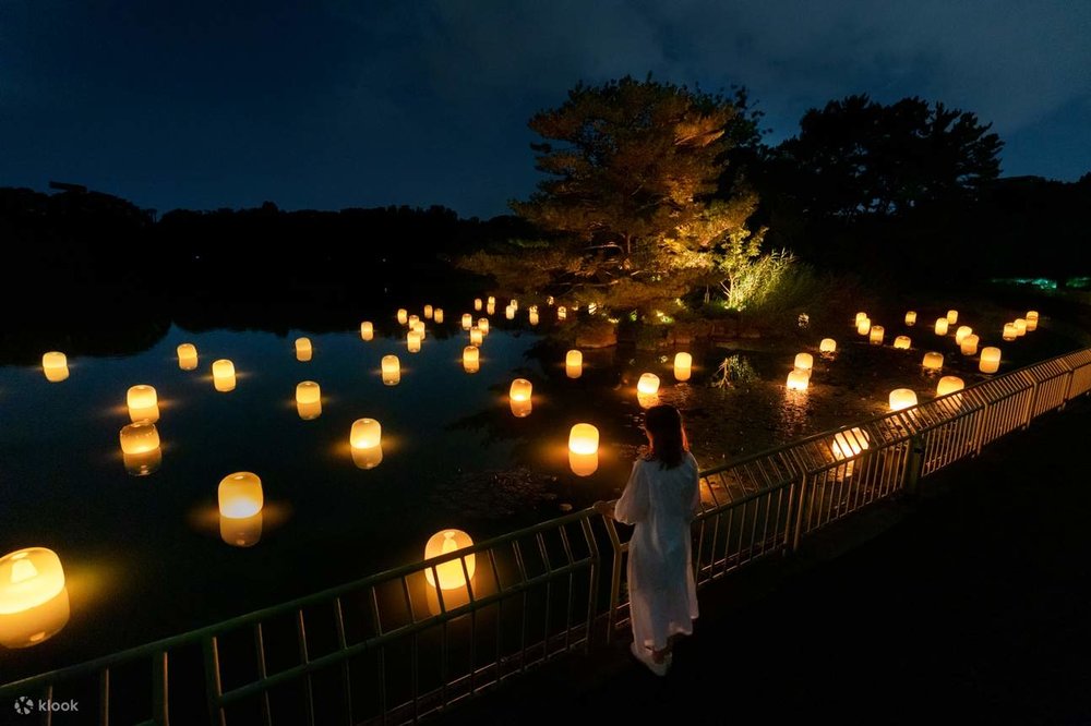 A woman looking out at a body of water full of lit lanterns