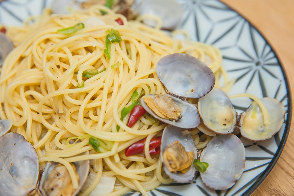 Close-up of spaghetti with clams, chili, and herbs on a patterned plate