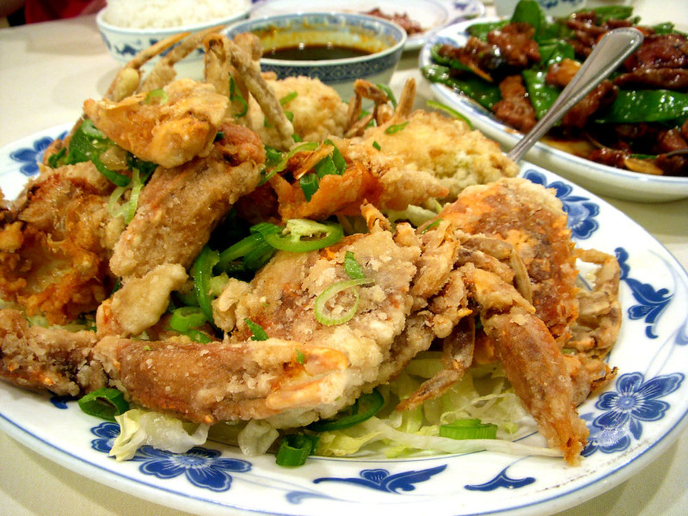 Plate of golden fried soft shell crab with green peppers and garnish
