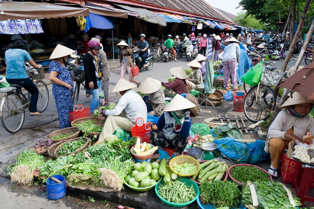 Vendors selling fresh vegetables at a busy Hoi An street market