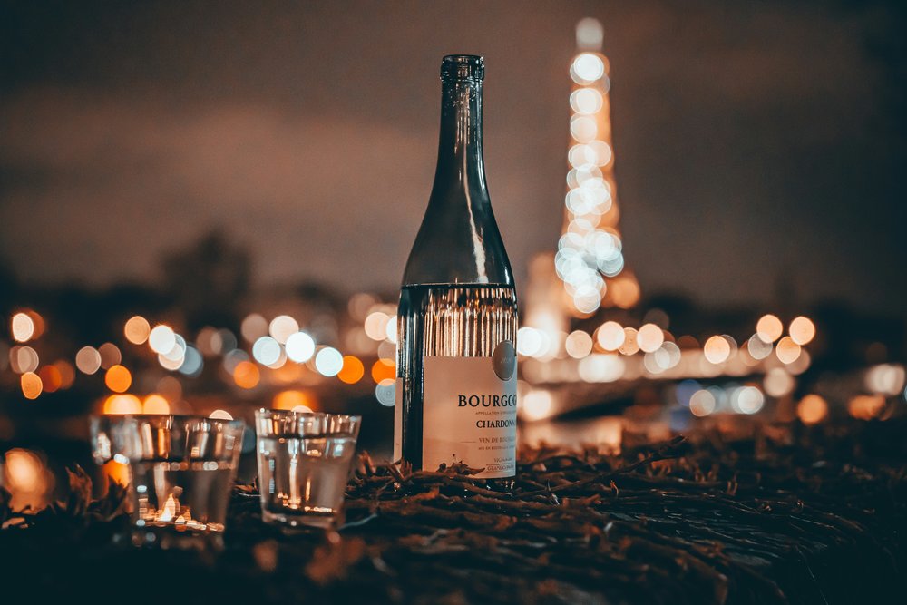 Bottle of Chardonnay wine with glasses overlooking the Eiffel Tower at night | Photo Credit: Mingrui He on Unsplash 