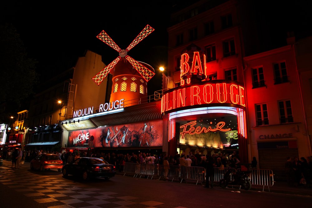Moulin Rouge entrance glowing with red neon lights at night in Paris | Photo Credit: Wikimedia Commons