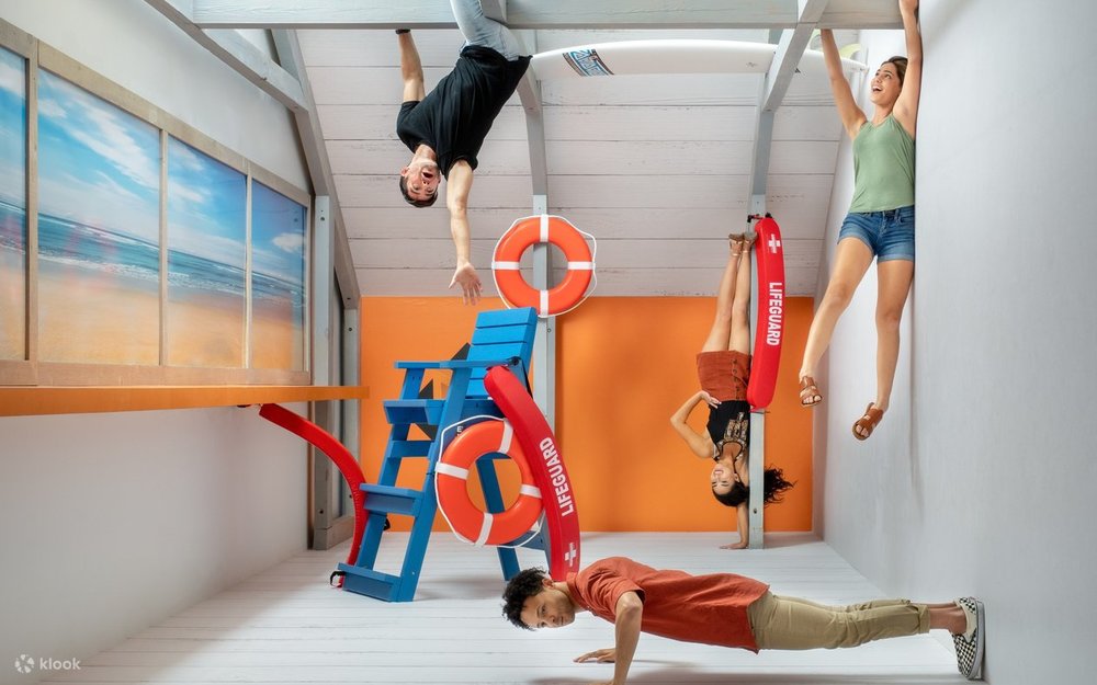 Visitors posing in a reversed illusion room at Museum of Illusions Orlando with lifeguard props and chairs appearing upside down