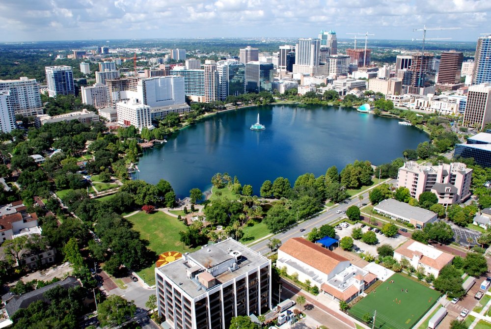 Aerial view of Lake Eola in Downtown Orlando with the fountain centered and high-rise buildings surrounding the lake
