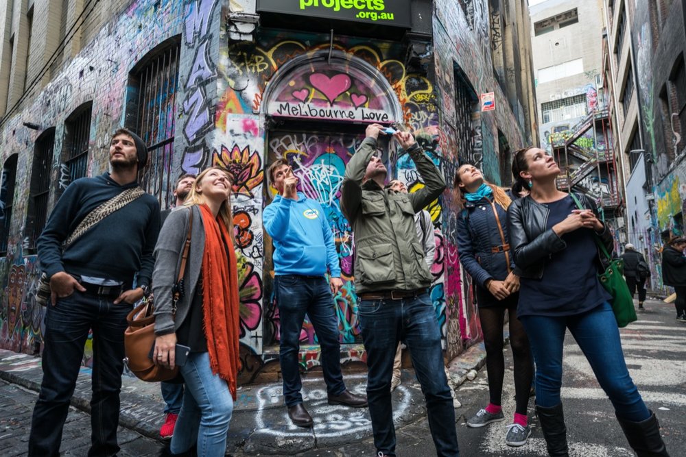 Travelers admiring colorful graffiti during a Melbourne street art walking tour