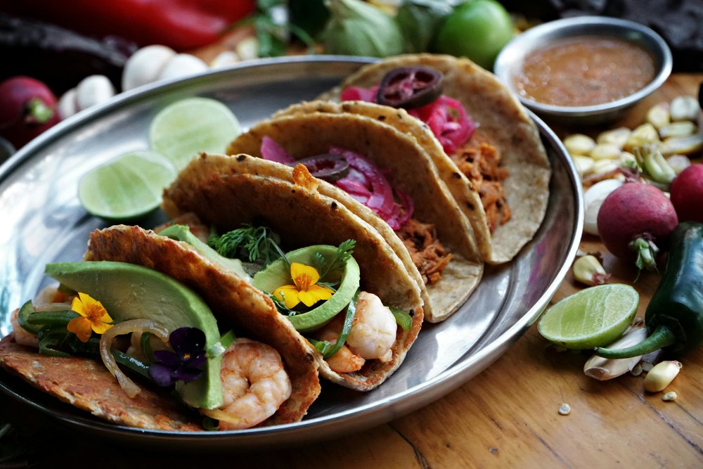 Street tacos with shrimp, avocado, and pickled onions on plate