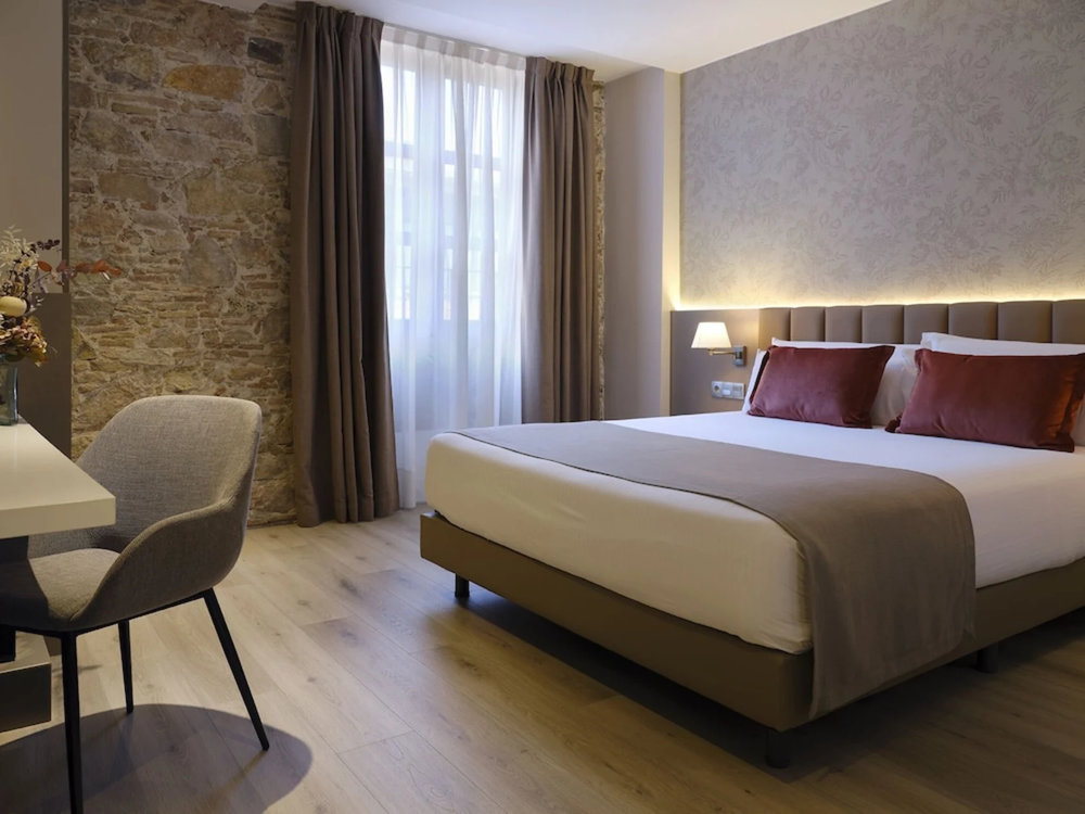Musik Boutique Hotel Barcelona bedroom with stone wall and warm lighting