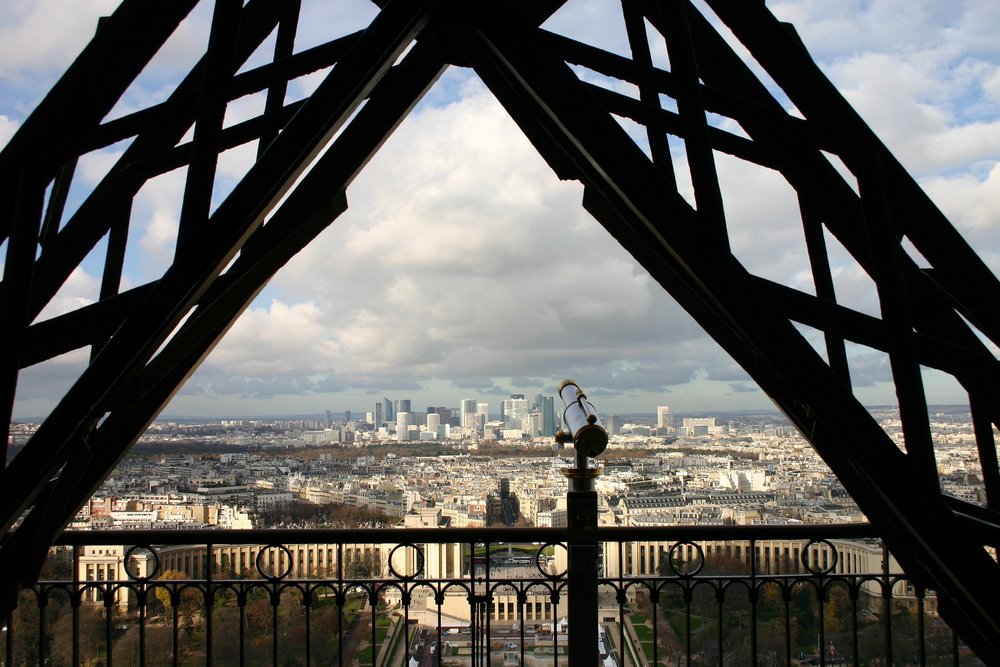 Paris city view framed by Eiffel Tower beams and telescope