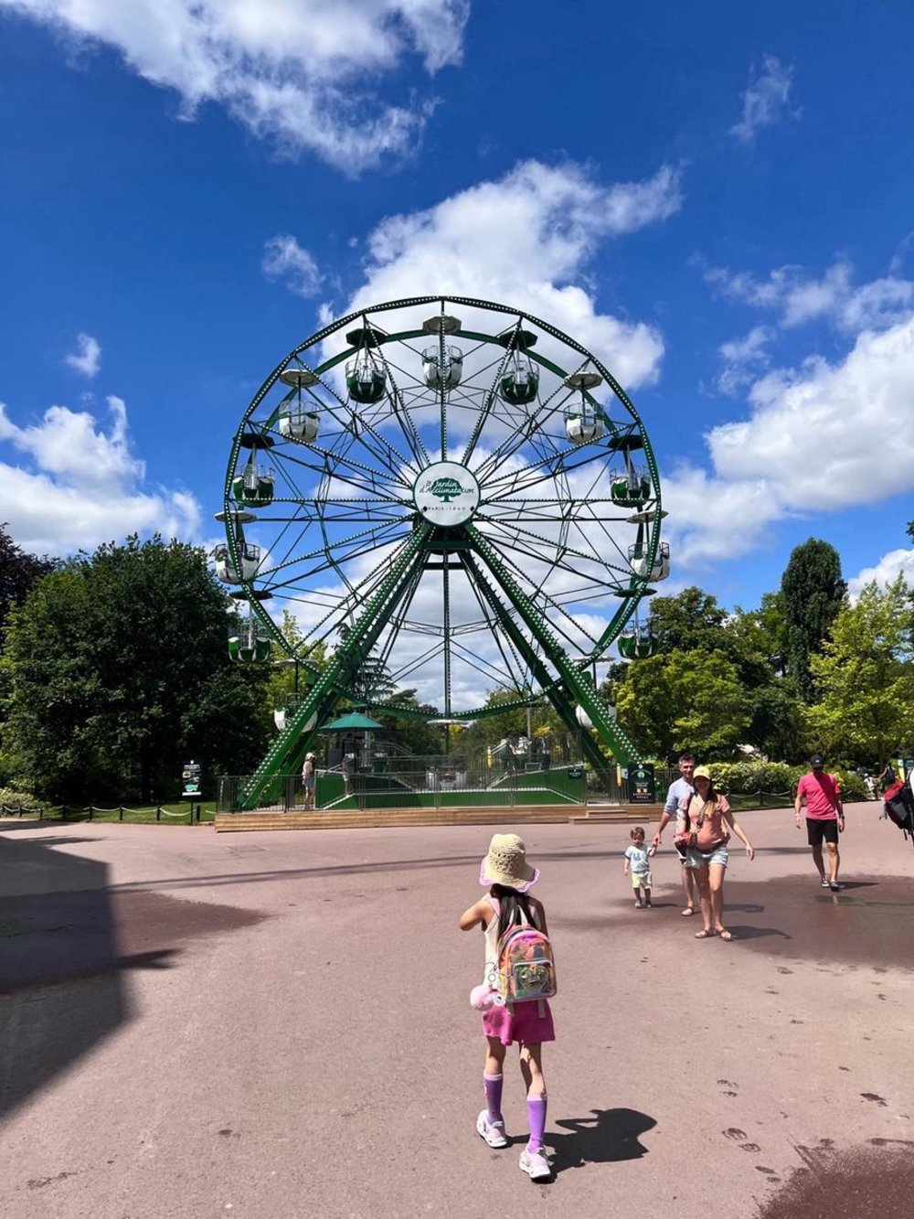 Child with backpack walking to Ferris wheel in Paris amusement park