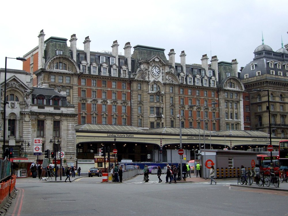 London Victoria Station's iconic façade, with buses and pedestrians nearby