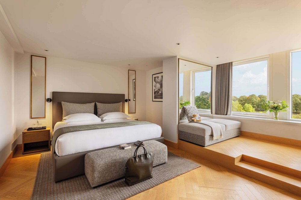 Hotel room with a four-poster bed, elegant décor, and a view of the greenery outside