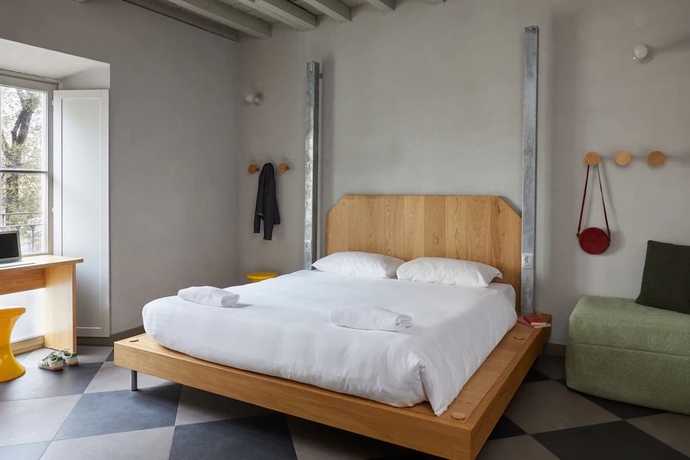 Minimalist room at Combo Milano Hostel with wooden platform bed and stylish decor