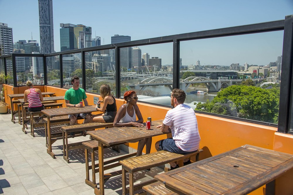 Friends enjoying drinks at a Melbourne rooftop bar overlooking the city skyline