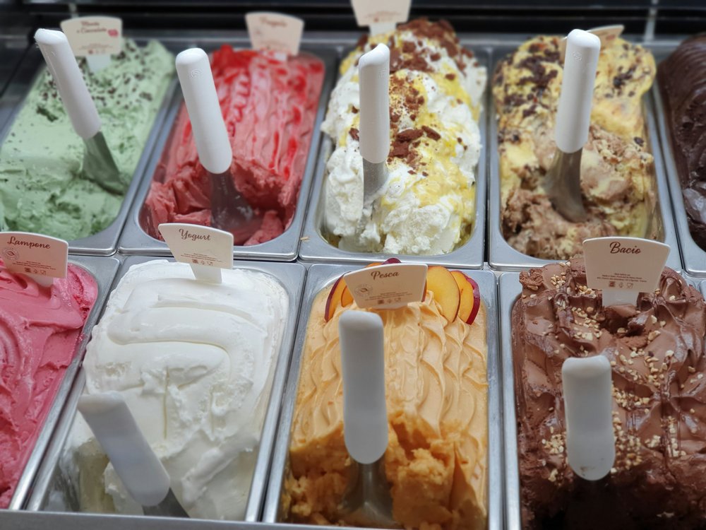 A variety of colorful gelato flavors like pistachio, yogurt, and strawberry in metal containers | Photo Credit: ROMAN ODINTSOV on Pexels