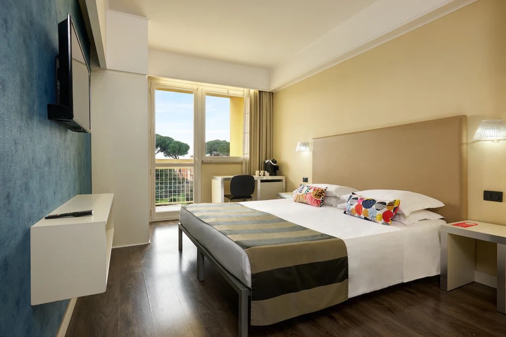 Bright hotel room at Hotel Roma Tor Vergata with double bed, desk, and balcony in Rome