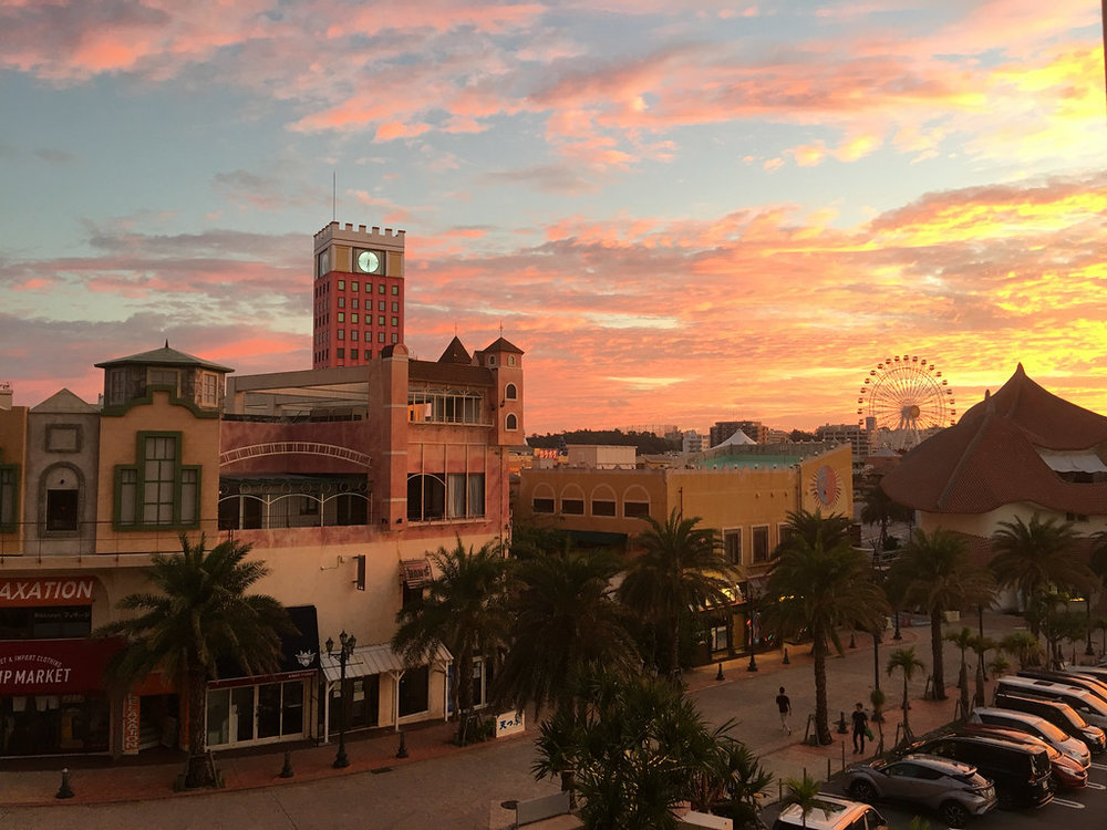 American Village buildings at sunset with Ferris wheel | Photo Credit: Wikimedia Commons