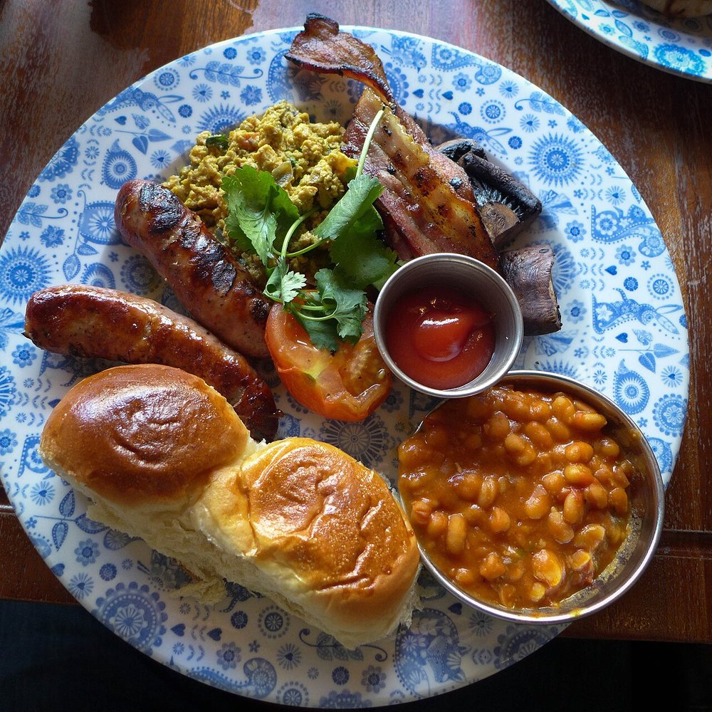 A plate of full English breakfast featuring sausages, eggs, toast, and beans