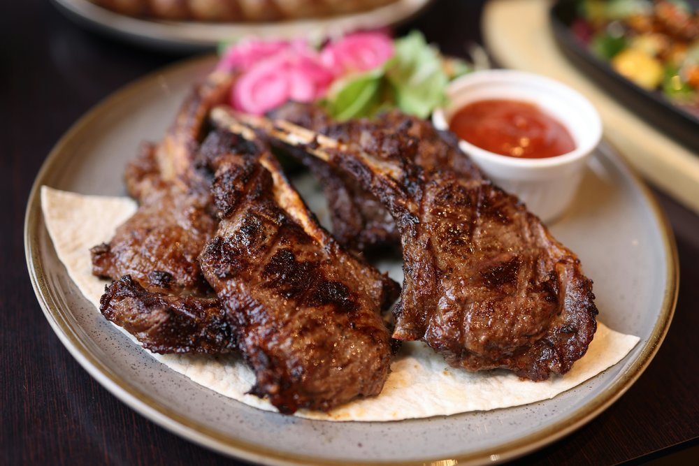 Grilled lamb ribs garnished with fresh herbs and served with dipping sauce