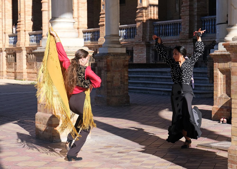 Two flamenco dancers performing under the sunlight in Seville, showcasing the art of flamenco.