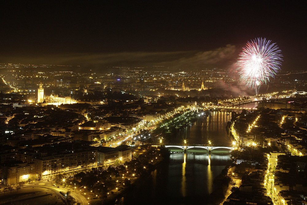 Seville’s skyline at night with fireworks above the Guadalquivir River during a festive celebration