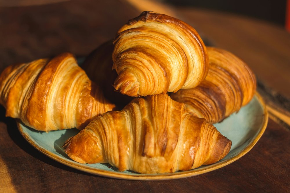 Golden flaky croissants served on a plate in Paris bakery