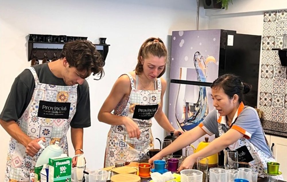 2 people learning how to make coffee from a Vietnamese instructor