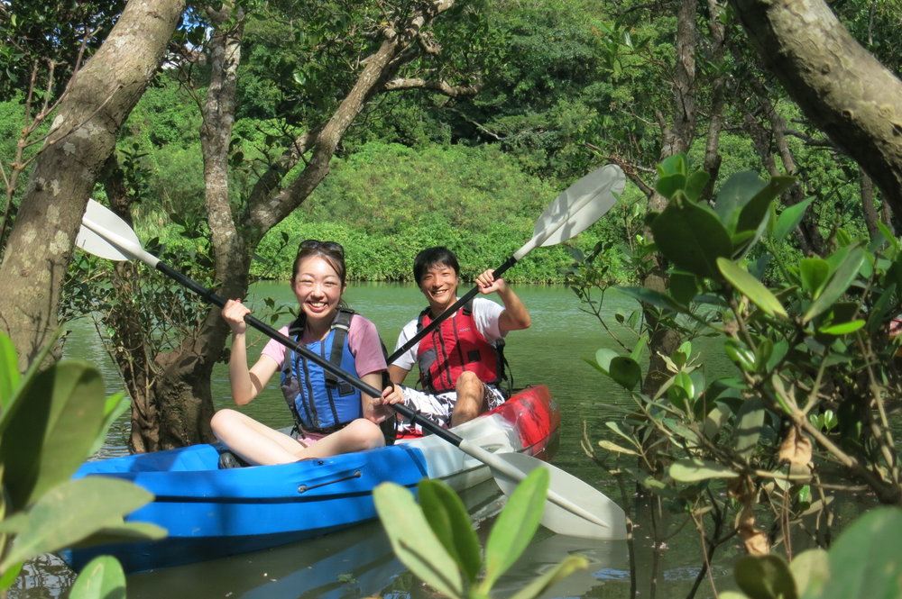 Couple kayaking through lush mangrove forest in Okinawa