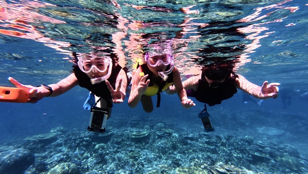 Friends snorkeling in tropical Okinawa waters with coral below