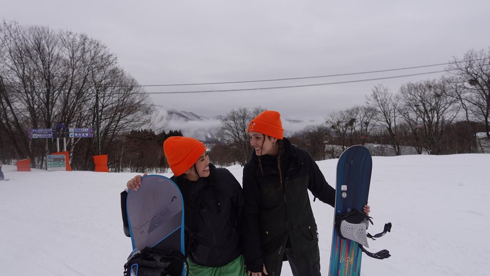 Two snowboarders smiling at a snowy ski resort in Japan
