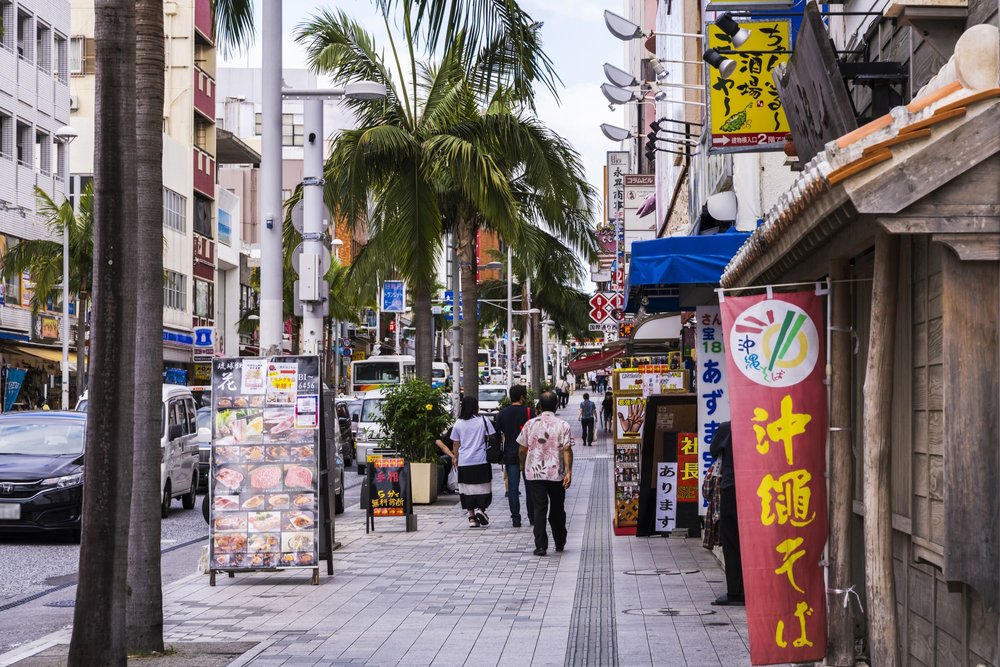 Palm trees and local shops along a lively Okinawa street