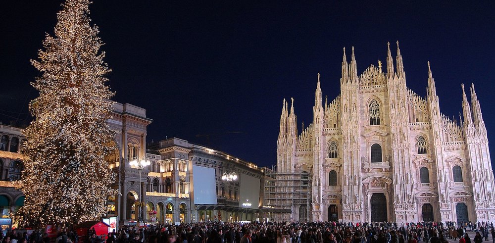 A huge christmas tree stands in front of the Duomo Cathedral, while a crowd of people stand in between them