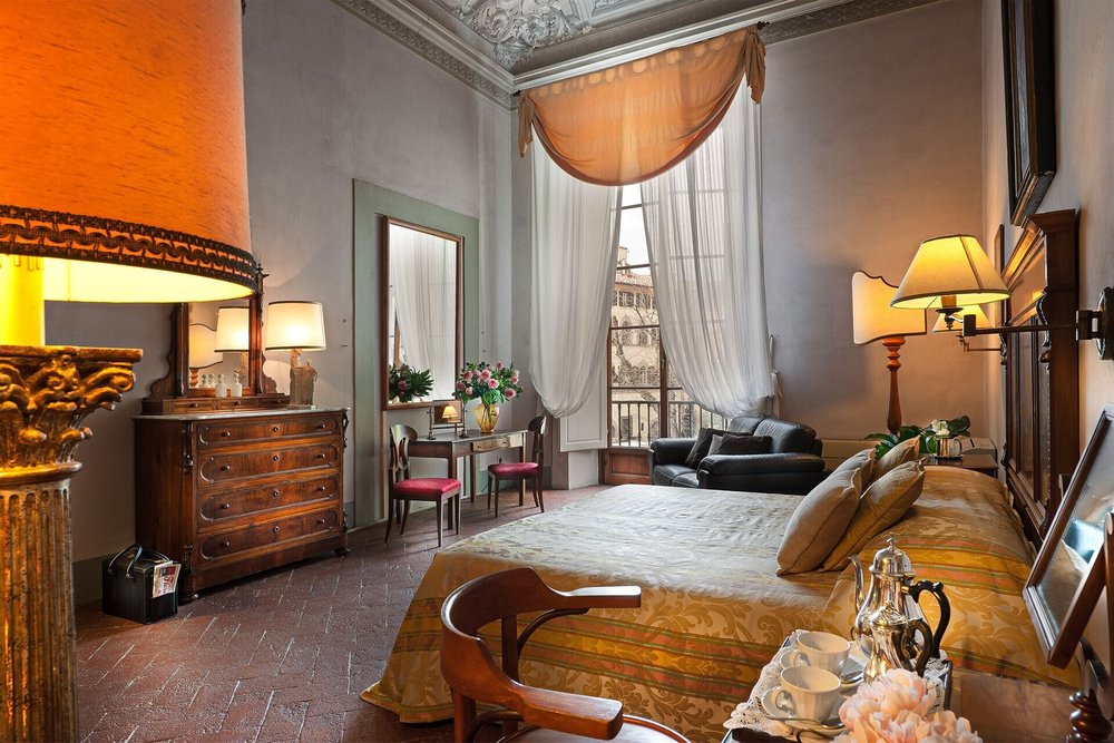Elegant Renaissance-style room at Hotel Palazzo Guadagni with antique furniture and tall windows
