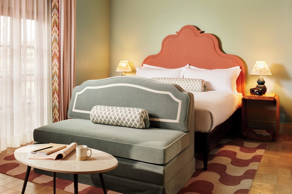 Modern boutique hotel room at The Hoxton Florence with coral headboard and cozy seating