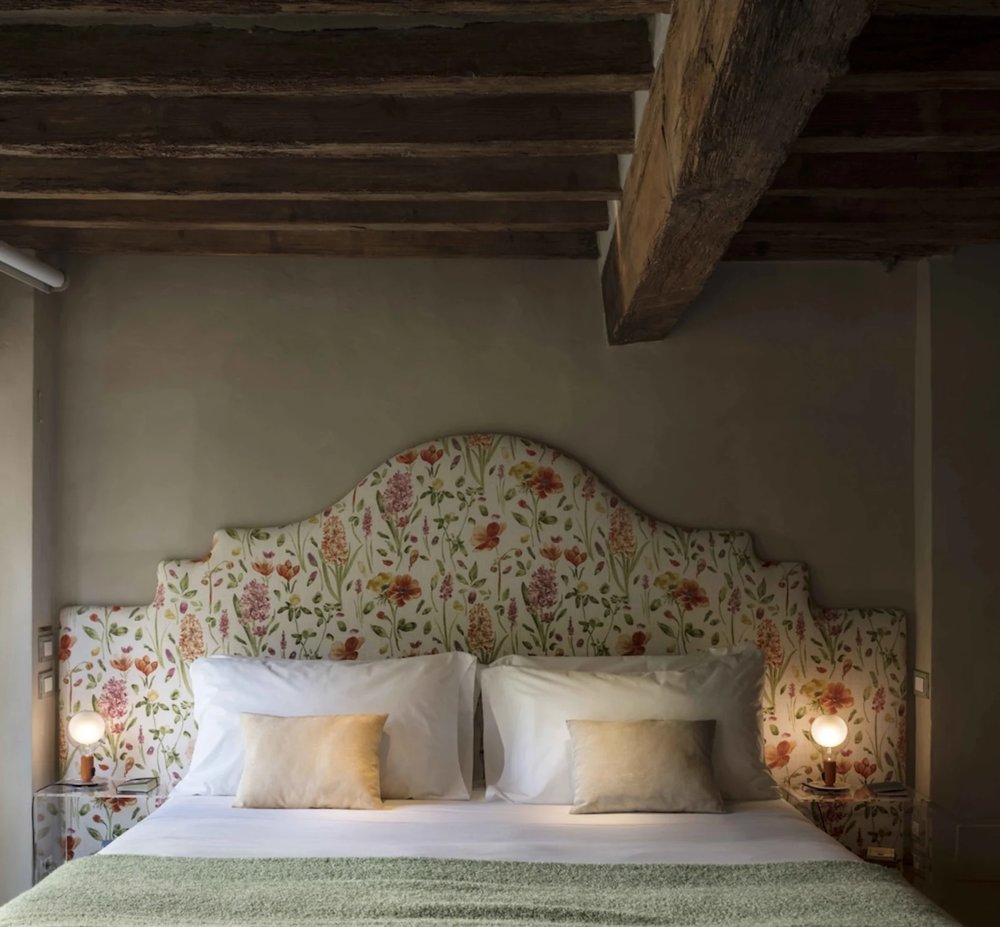 Intimate guest room at Ottantotto Firenze featuring wooden beams and elegant floral decor