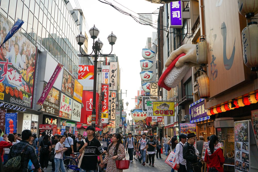 Busy Dotonbori street in Osaka with neon signs, restaurants, and tourists