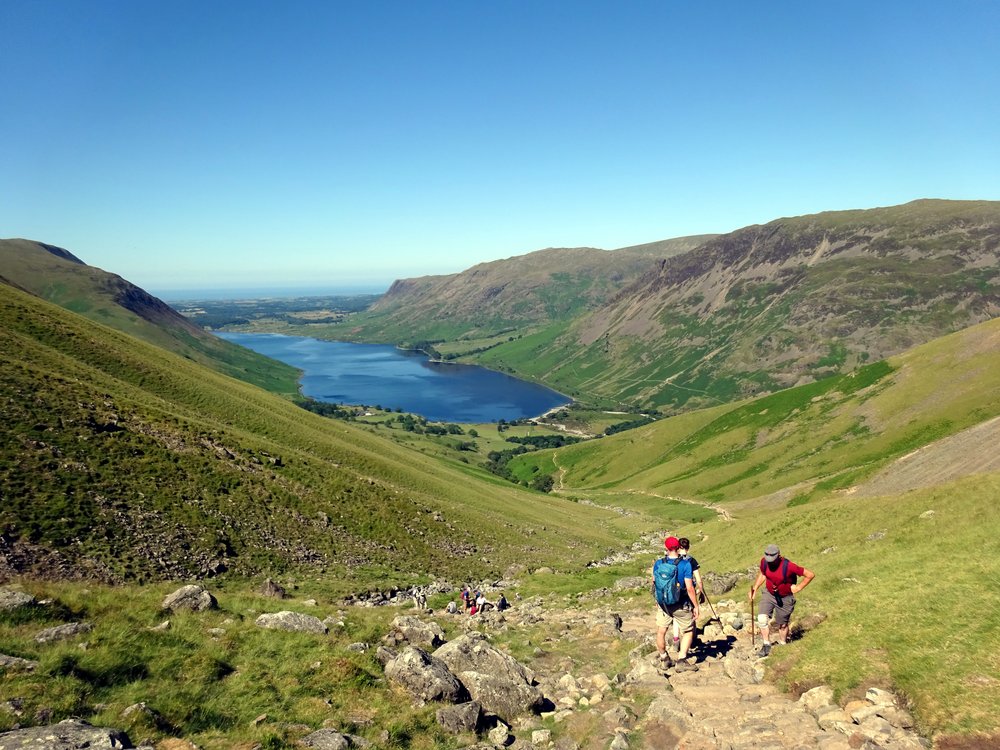 Hikers descending Scafell Pike trail with Lake District valley views, England
