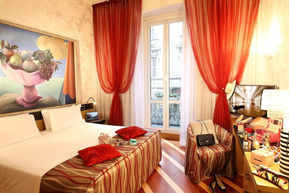Hotel Sanpi Milano guest room interior with red curtains and balcony