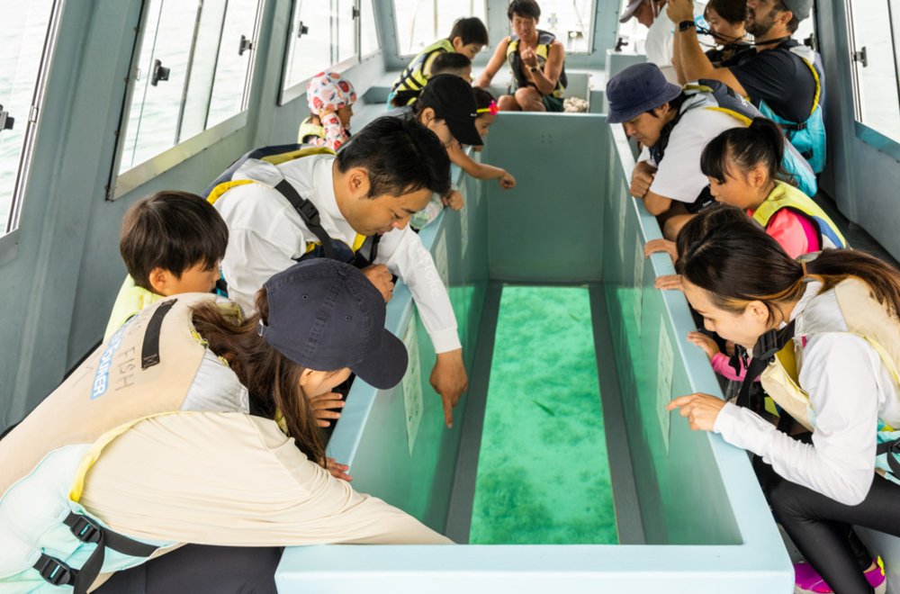 Visitors viewing fish and coral through a glass-bottom boat in Okinawa