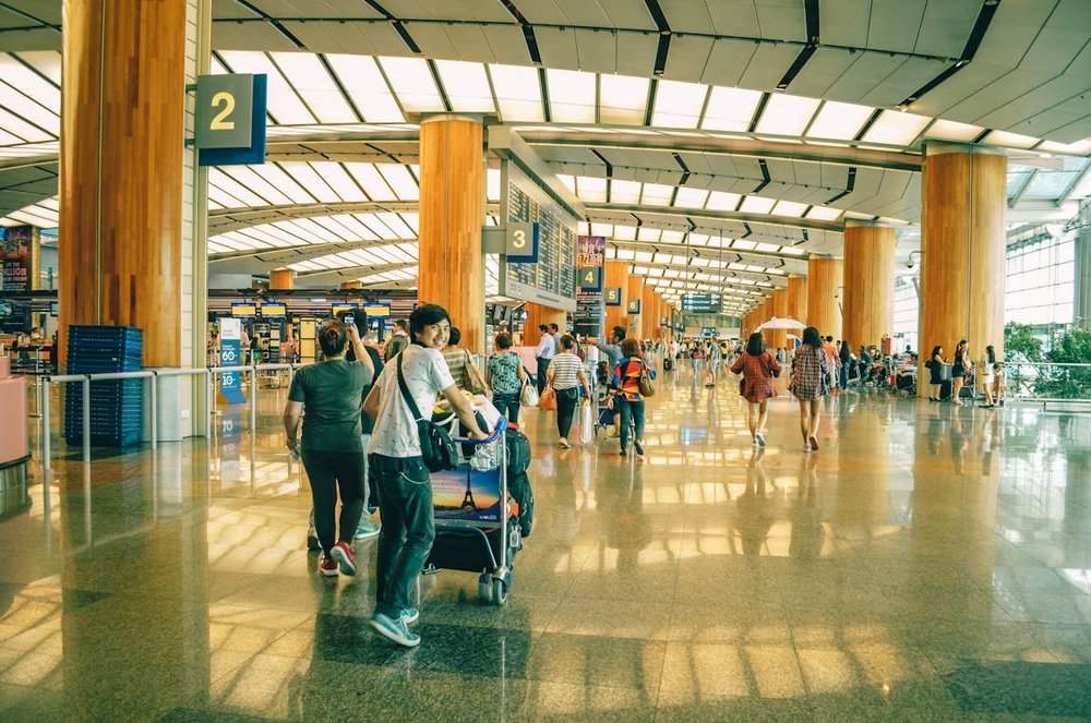 Person walking through Singapore Airport pushing a luggage card and looking back