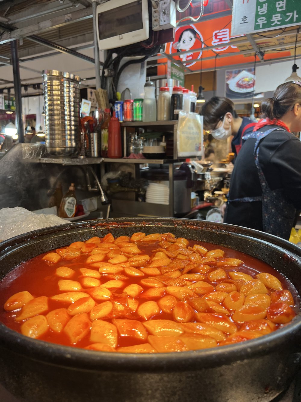 Tteokbokki rice cakes cooking in red chili sauce at a Seoul street food market stall