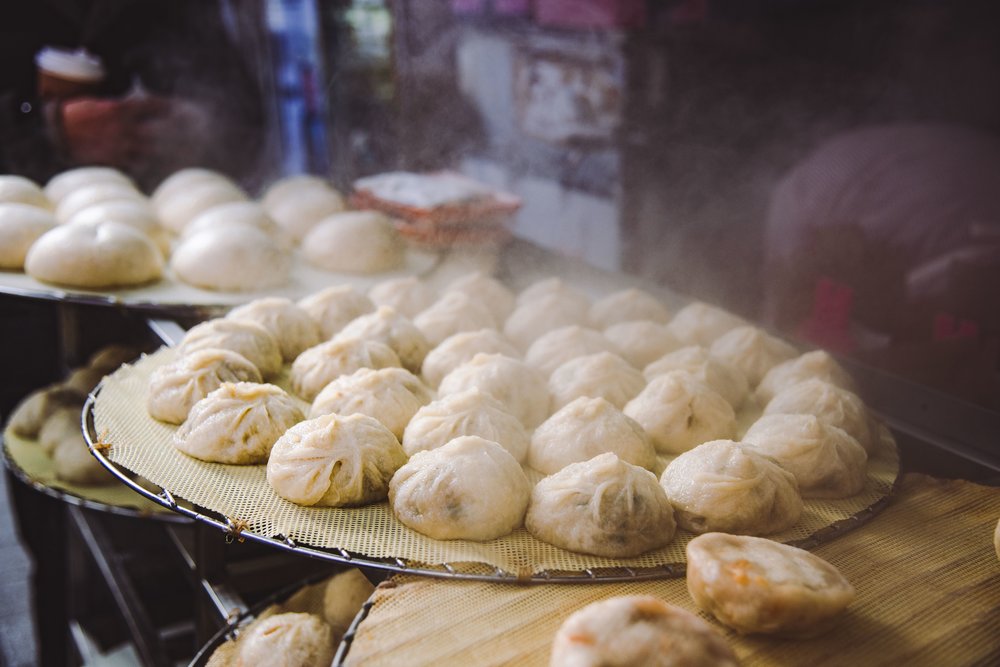 Korean mandu dumplings steaming on trays at a Seoul street food market