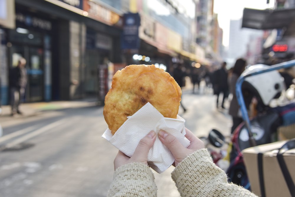 Korean hotteok sweet pancake held on a Seoul street food market street