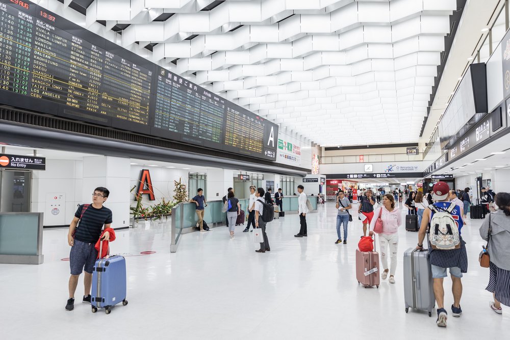 Passengers walking through Japan airport arrival hall with suitcases
