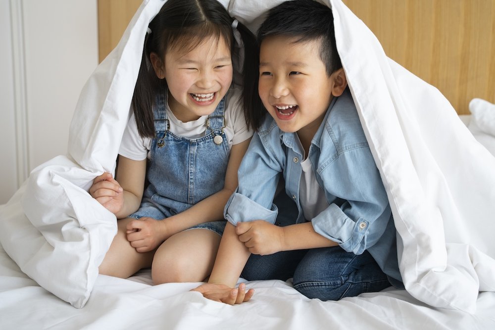 Kids under a blanket at a hotel
