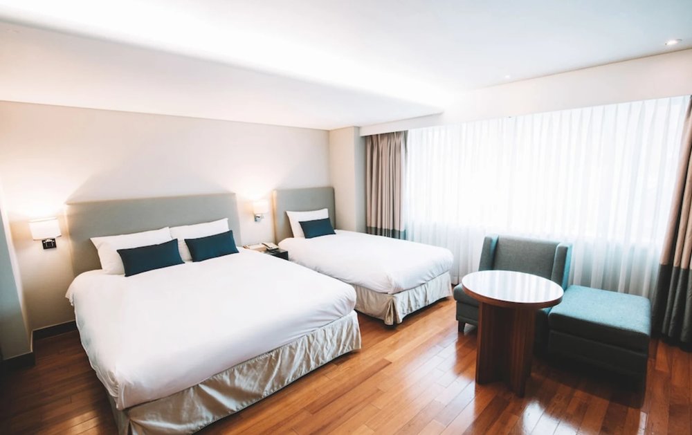 Large hotel room with two beds and seating area at Hotel Prince Seoul in Myeongdong