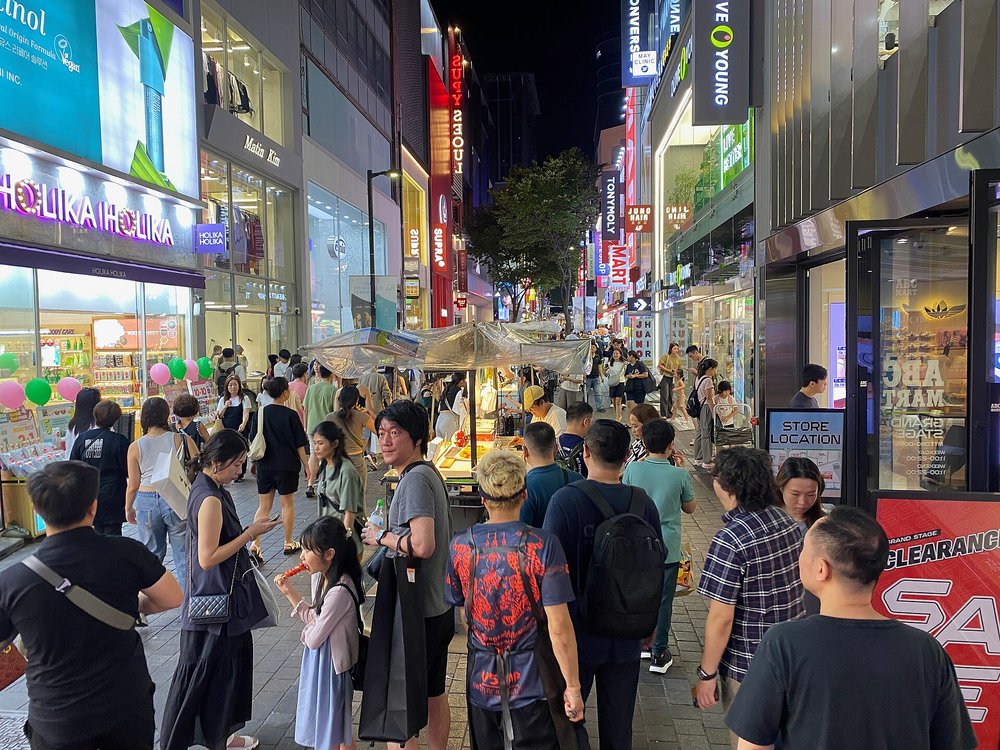 Busy Myeongdong shopping street with K-beauty stores and night market stalls
