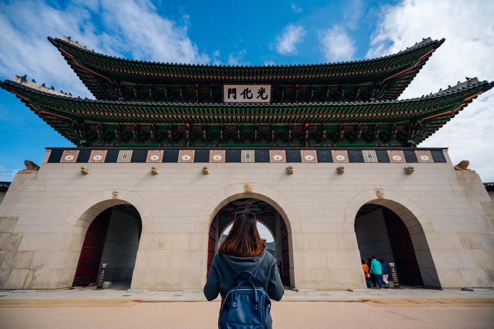 Traveler at Gyeongbokgung Palace gate in Seoul with traditional architecture